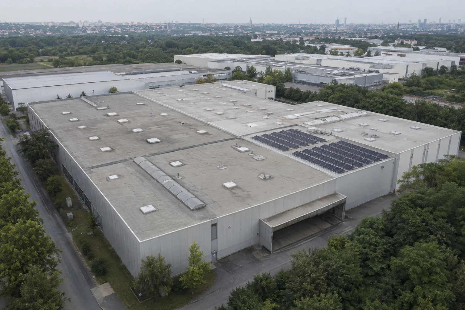 Illustrative Luftansicht einer Gewerbehalle mit Dachaufbauten und Solarmodulen